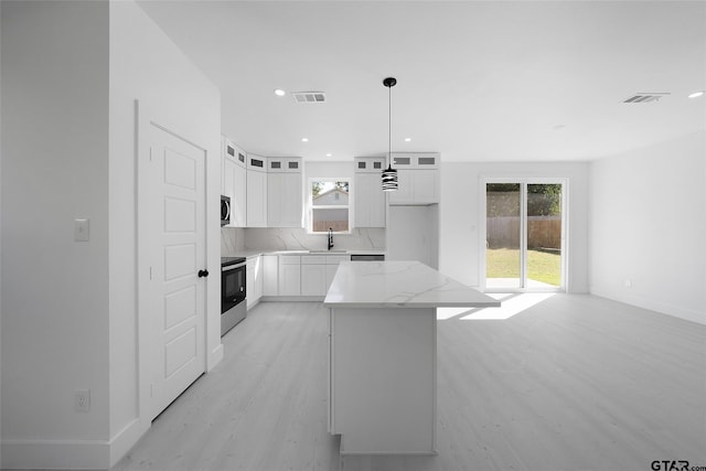 kitchen with stainless steel appliances, white cabinetry, plenty of natural light, and a center island