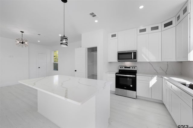 kitchen featuring pendant lighting, stainless steel appliances, white cabinetry, and a center island