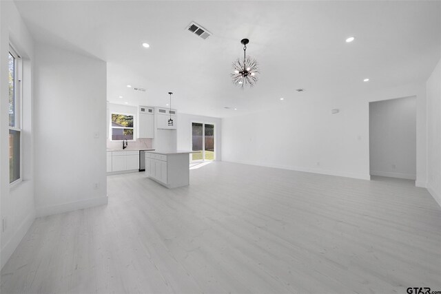 unfurnished living room with a chandelier, sink, and light hardwood / wood-style flooring