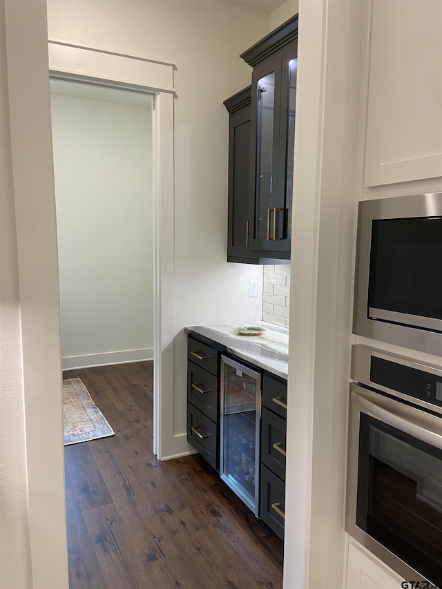 kitchen featuring oven, decorative backsplash, built in microwave, dark hardwood / wood-style flooring, and beverage cooler