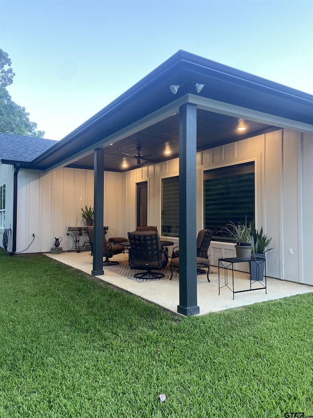 back of property with ceiling fan, a yard, and a patio