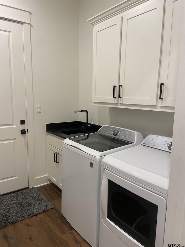 washroom featuring dark hardwood / wood-style floors, cabinets, sink, and washing machine and clothes dryer