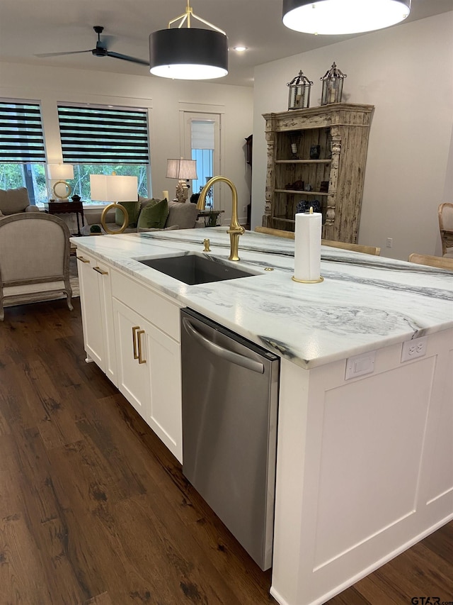 kitchen featuring light stone counters, stainless steel dishwasher, sink, white cabinets, and hanging light fixtures