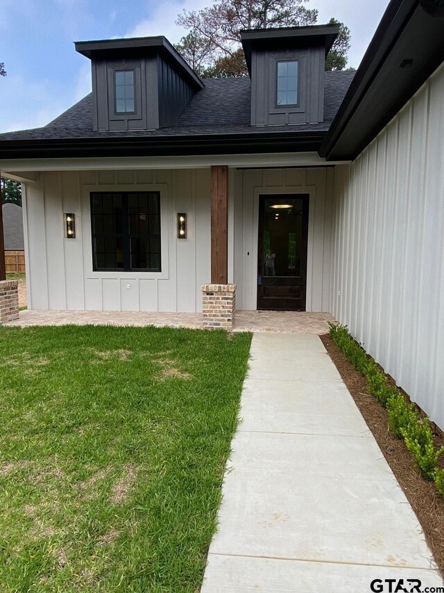 doorway to property with a porch and a yard