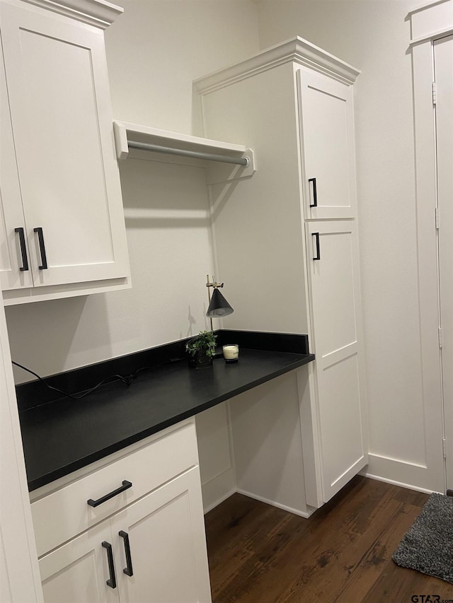 kitchen with white cabinets, built in desk, and dark hardwood / wood-style floors