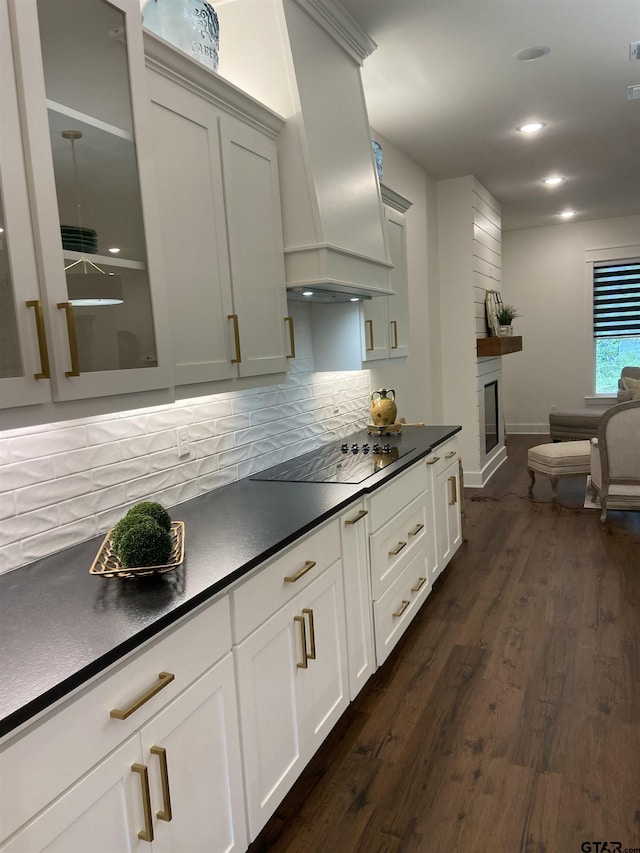 kitchen with black electric stovetop, custom range hood, a large fireplace, dark hardwood / wood-style floors, and white cabinetry