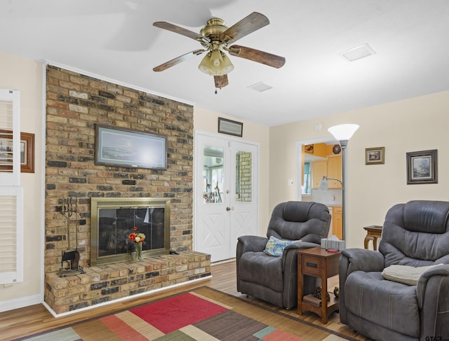 living room with hardwood / wood-style flooring, ceiling fan, and a fireplace