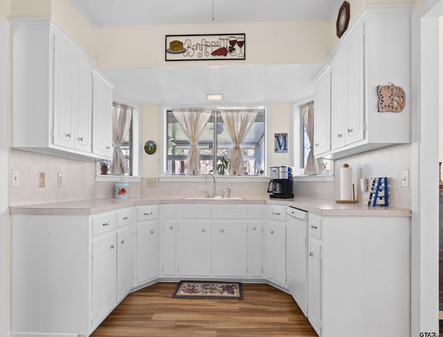 kitchen with dishwasher, white cabinetry, sink, and light hardwood / wood-style floors