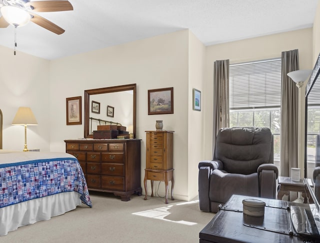 bedroom featuring ceiling fan, light carpet, and a textured ceiling