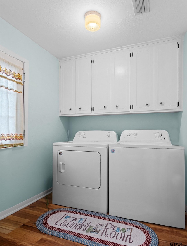 laundry room with cabinets, hardwood / wood-style flooring, and washer and clothes dryer