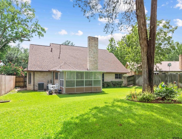 back of property with central AC unit, a sunroom, and a lawn