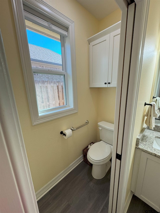 bathroom with toilet, vanity, baseboards, and wood finished floors