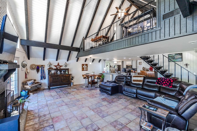 living room with ceiling fan, beam ceiling, wood walls, and high vaulted ceiling