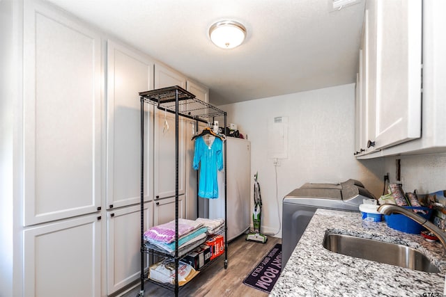 clothes washing area with cabinets, sink, independent washer and dryer, and light wood-type flooring