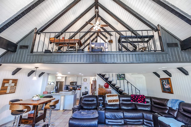 tiled living room featuring beam ceiling, ceiling fan, wood walls, and high vaulted ceiling