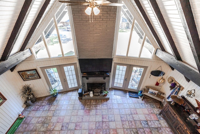 living room with wood walls, a fireplace, french doors, and high vaulted ceiling