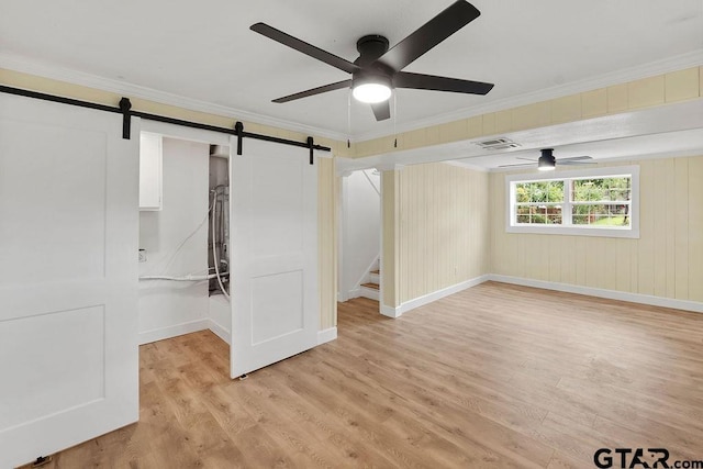 2442 E Devine, Tyler, TX 75701 - empty room with a barn door, ornamental molding, a ceiling fan, light wood-type flooring, and baseboards