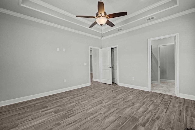 unfurnished bedroom featuring a raised ceiling, hardwood / wood-style flooring, ceiling fan, and crown molding