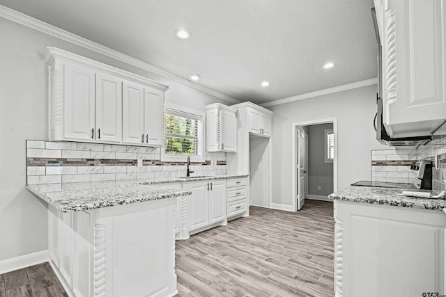 kitchen featuring white cabinets, light stone countertops, light wood-type flooring, and tasteful backsplash