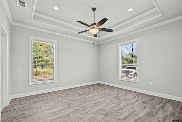 unfurnished room featuring light hardwood / wood-style flooring, ceiling fan, crown molding, and a tray ceiling