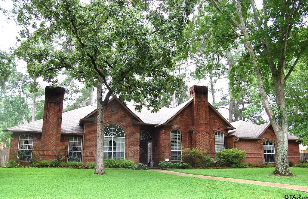 1683 Old Oak Dr, Tyler, TX 75703 - view of front facade featuring a chimney, brick siding, and a front lawn