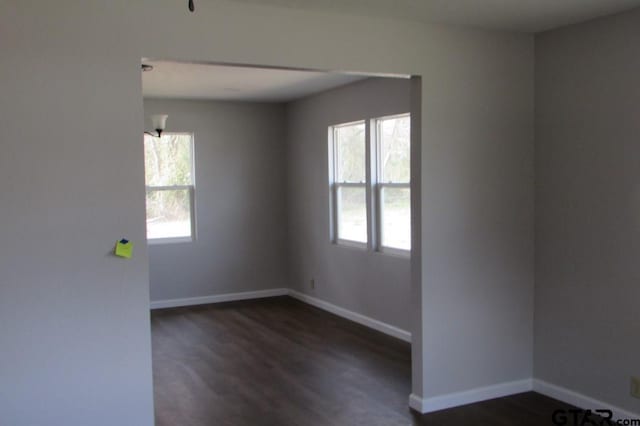 empty room featuring dark wood-style flooring and baseboards