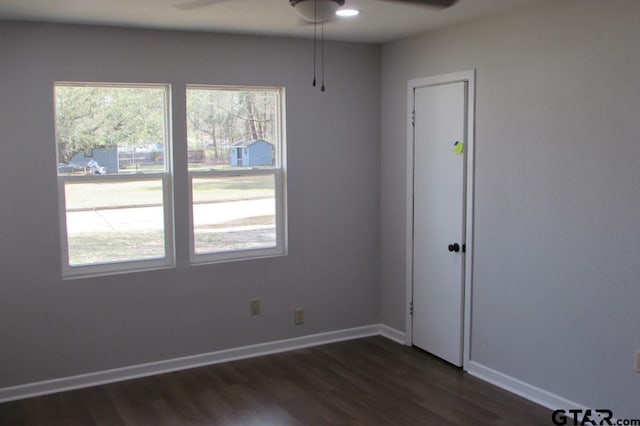 empty room with a ceiling fan, baseboards, and dark wood-type flooring