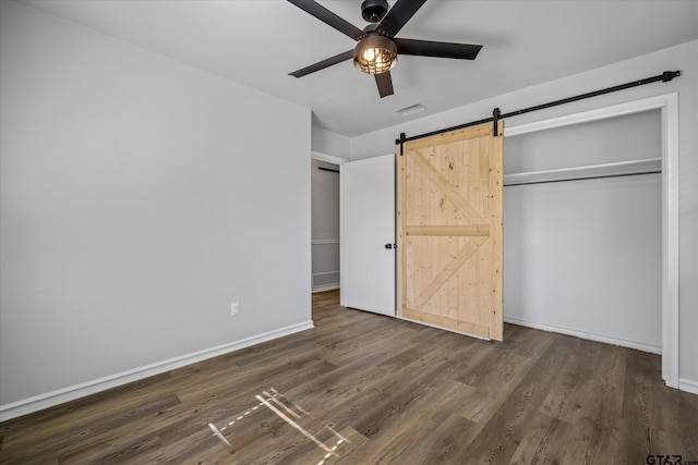 2014 Miller Dr, Tyler, TX 75701 - unfurnished bedroom featuring a barn door, dark wood finished floors, baseboards, and a ceiling fan