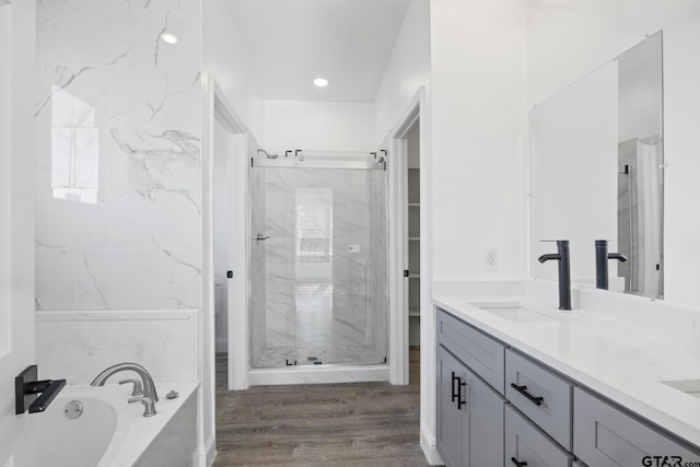 bathroom featuring hardwood / wood-style flooring, vanity, and plus walk in shower