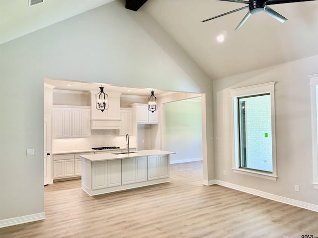 kitchen featuring light countertops, high vaulted ceiling, baseboards, and a sink