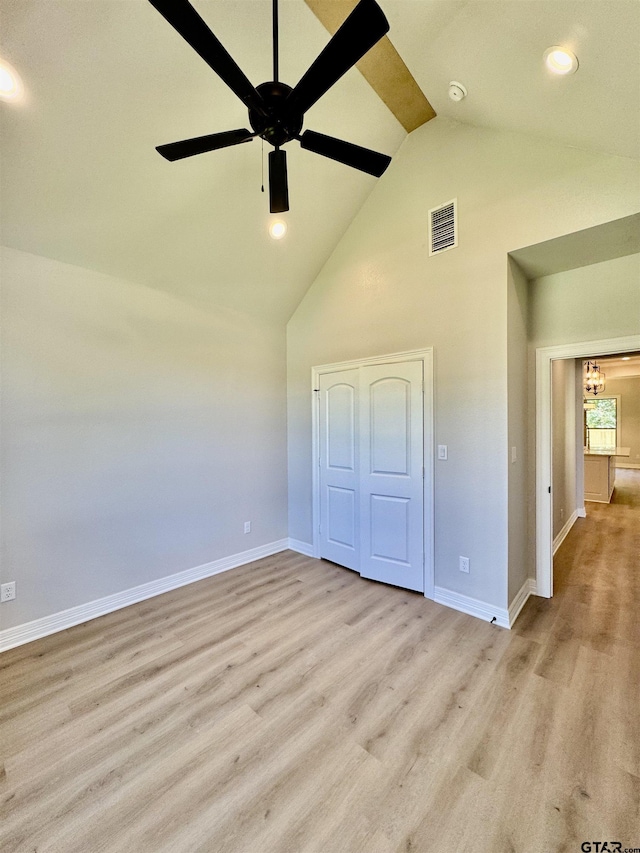 unfurnished bedroom with visible vents, baseboards, wood finished floors, and high vaulted ceiling