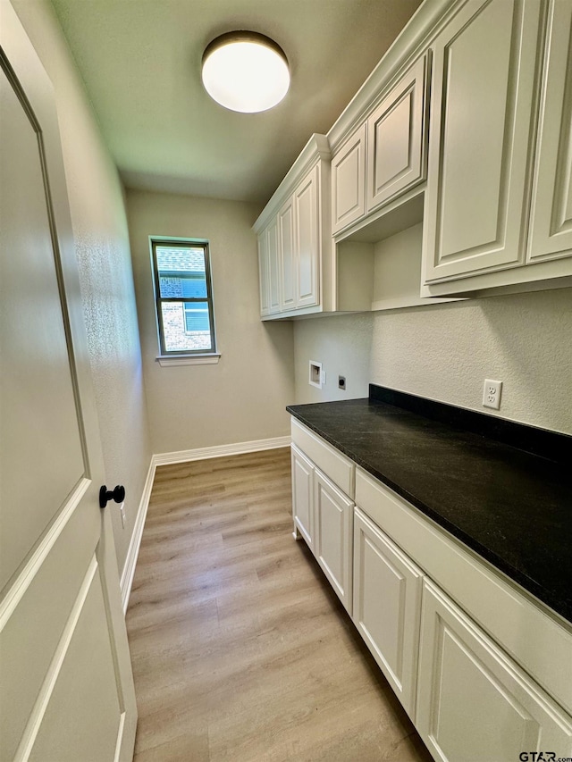 washroom with baseboards, hookup for a washing machine, light wood finished floors, hookup for an electric dryer, and cabinet space