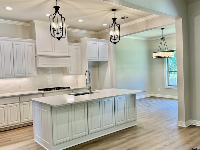 kitchen with an inviting chandelier, a sink, gas stovetop, light countertops, and white cabinets