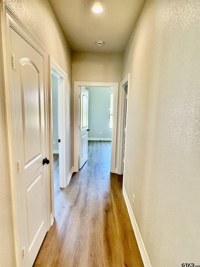 corridor with baseboards and wood finished floors
