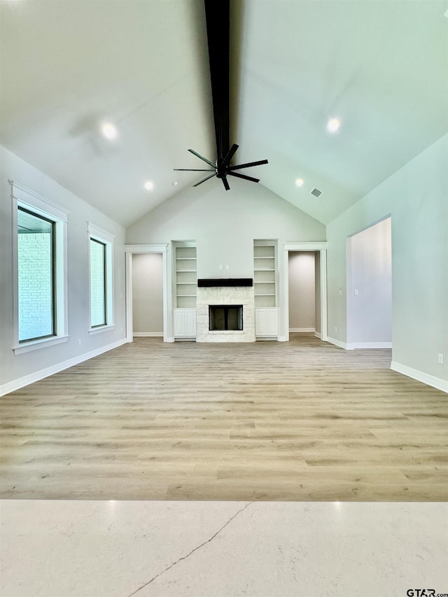 unfurnished living room with a ceiling fan, vaulted ceiling with beams, built in features, baseboards, and visible vents