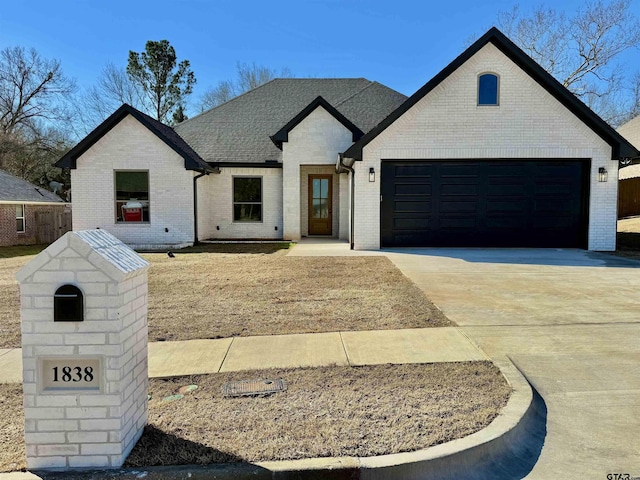 view of front of house with driveway, brick siding, roof with shingles, and an attached garage