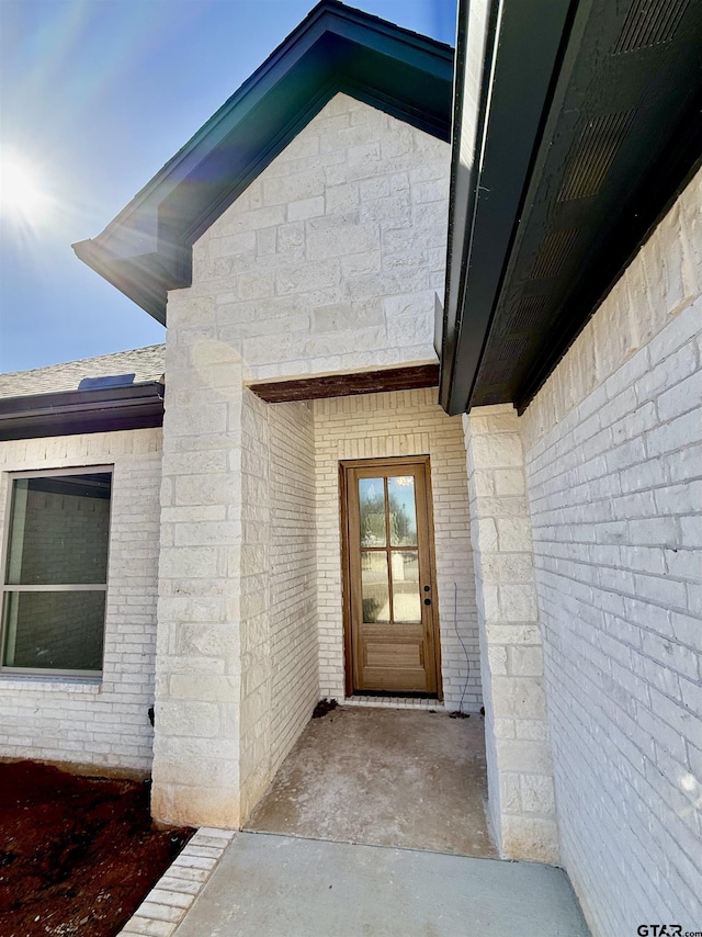 view of exterior entry featuring brick siding