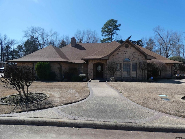 view of front of home with brick siding, a chimney, and roof with shingles