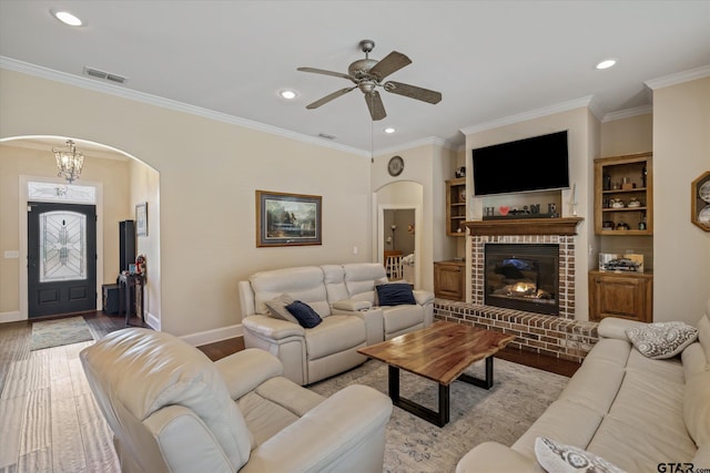 living room with arched walkways, light wood-type flooring, baseboards, and crown molding