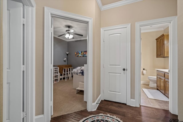 hall featuring baseboards, ornamental molding, and dark wood finished floors