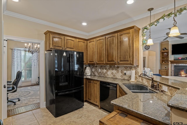 kitchen featuring a sink, dark stone counters, black appliances, brown cabinetry, and decorative light fixtures