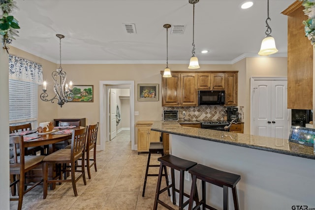 kitchen with black appliances, dark stone countertops, visible vents, and pendant lighting