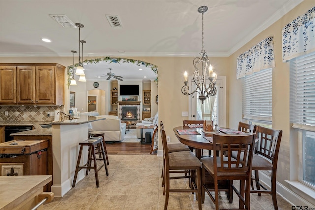 dining area featuring a brick fireplace, visible vents, and ornamental molding