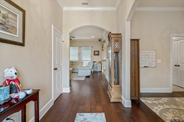 corridor with baseboards, arched walkways, dark wood finished floors, and crown molding