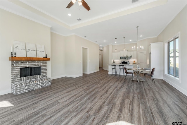 living room with crown molding, dark hardwood / wood-style floors, a fireplace, and ceiling fan