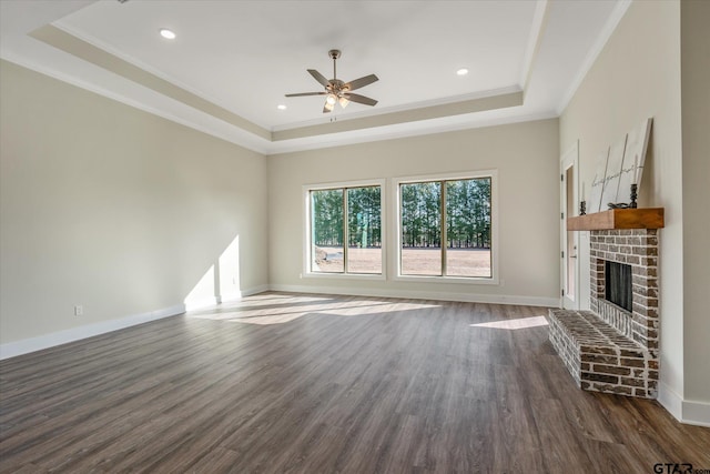 unfurnished living room featuring a fireplace, ornamental molding, dark hardwood / wood-style floors, and a raised ceiling