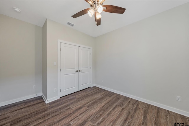 unfurnished bedroom featuring dark hardwood / wood-style floors, ceiling fan, and a closet