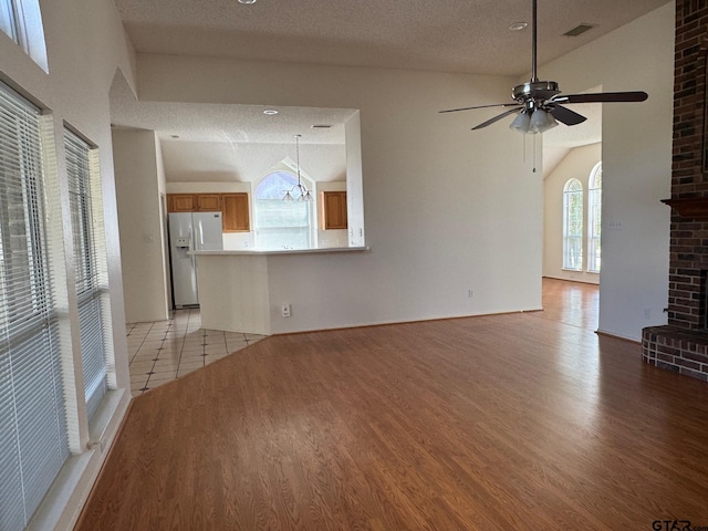 2414 Stillwater Dr, Mesquite, TX 75181 - unfurnished living room featuring light wood finished floors, lofted ceiling, a textured ceiling, and ceiling fan