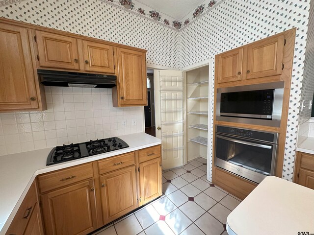 kitchen with tasteful backsplash, stainless steel appliances, and light tile patterned flooring