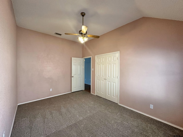 unfurnished bedroom featuring ceiling fan, lofted ceiling, a closet, and dark colored carpet